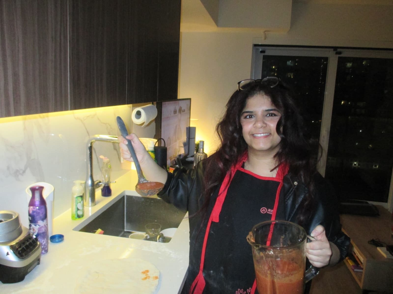 Sanya cooking and holding a drink